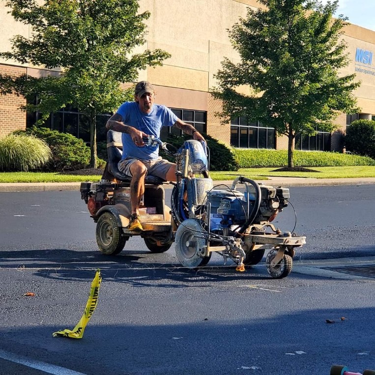 Parking lot striping machine applying paint on a commercial lot